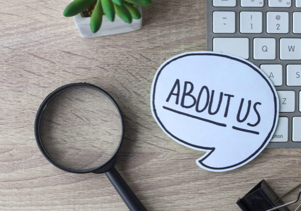 An about us speech bubble cut out and places on a keyboard and desk.