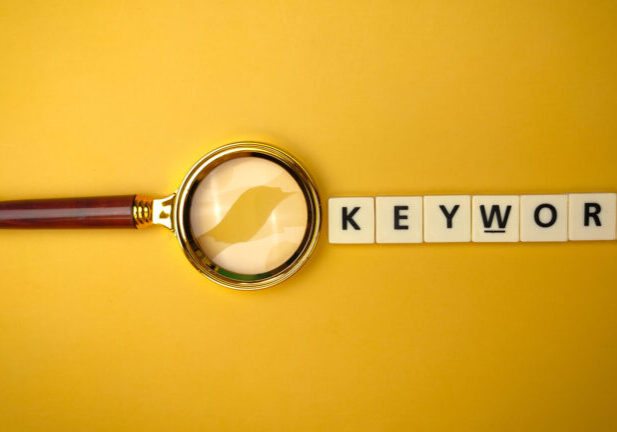 Magnifying glass and toys word with the word KEYWORD on yellow background