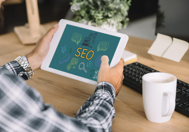 cropped shot of developer using tablet with SEO icons at workplace
